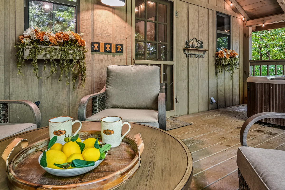 A bright, inviting living area with a comfortable seating arrangement, a wooden coffee table adorned with lemons, decorative flowers on the wall, and a hot tub area visible next to large windows that let in abundant natural light. The scene exudes a sense of relaxation and is perfect for gathering after a day of adventure.