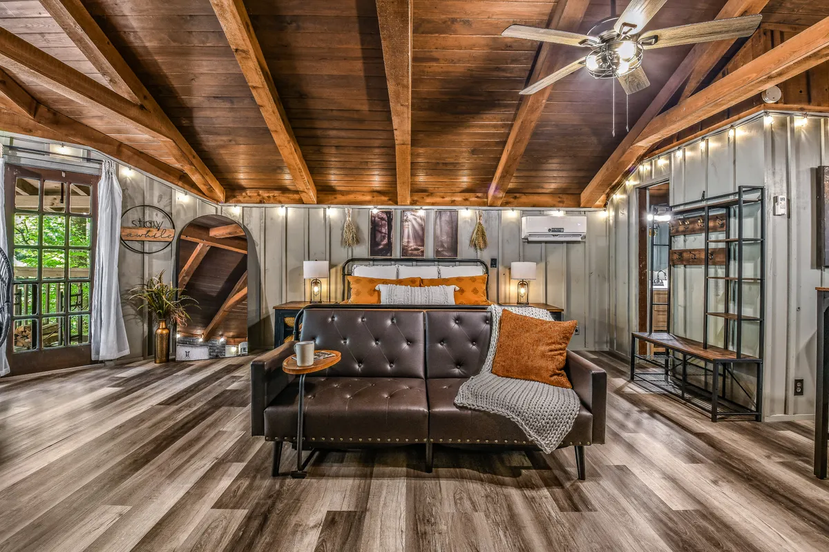 A unified space with a sofa and bed under rustic wooden beams, adorned with decorative details. The layout is clearly designed for both relaxation and socializing, making it ideal for small groups to enjoy time together whether it's for movie nights or chatting after an adventure.