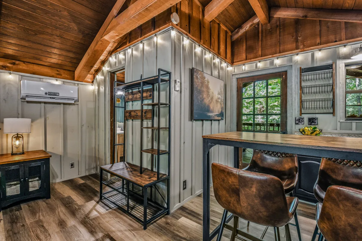 A welcoming dining area under a wooden ceiling, with a table perfect for shared meals or late-night games, decorated shelves, and large windows letting in plenty of natural light. The atmosphere is warm and sociable, suitable for intimate dinners or casual group gatherings.