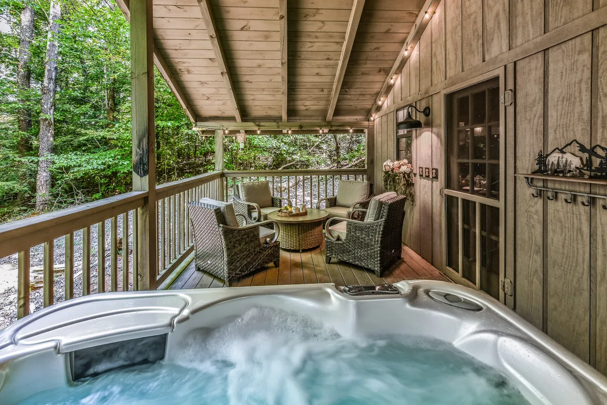 This exterior image showcases a relaxing hot tub set on a deck with comfortable seating and surrounded by lush trees. The natural setting conveys a sense of tranquility, and the outdoor amenities highlight opportunities for unwinding after a day of adventure.