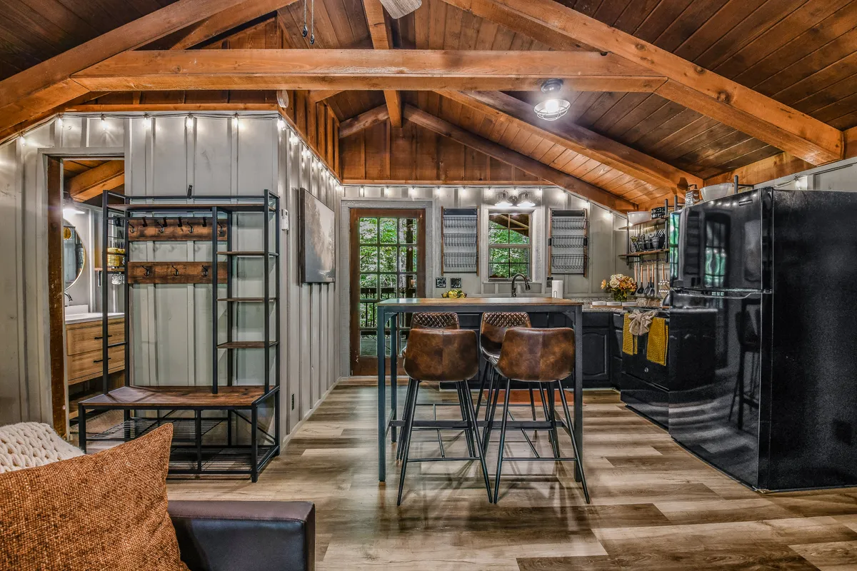A stylish kitchen area with a center island, bar stools, rich wooden beams, and modern lighting fixtures. The kitchen is both functional and welcoming, supporting family meal preparation and casual dining.